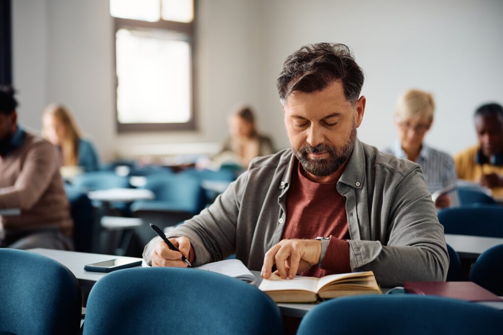 Mature man studying while attending adult education training class in the classroom.